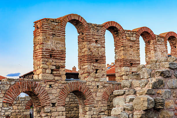 Ancient roman stone arches against blue sky in historical ruins.