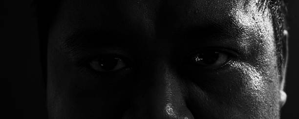istock Dark moody portrait capturing both eyes under harsh lighting, conveying tension, seriousness, and emotional strength in fine art monochrome. 2243580964