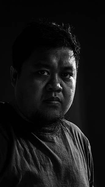 istock Dramatic low key portrait of a man looking directly at camera, revealing intensity, self-confidence, and focus in high contrast lighting. 2243581374