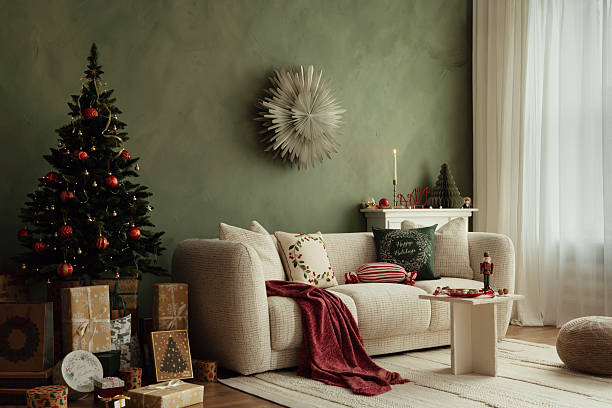 istock Christmas living room with decorated tree and presents under it. Cozy beige sofa, red throw blanket, and stylish holiday cushions. 2243581727