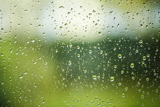 istock raindrops on window glass with blurred green background 2243583809