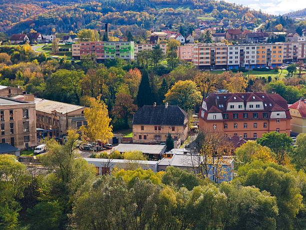 Roztoky u Krivoklatu, Czech republic - October 25, 2025: town cityscape with residential and industrial buildings amid vibrant autumn trees on hills