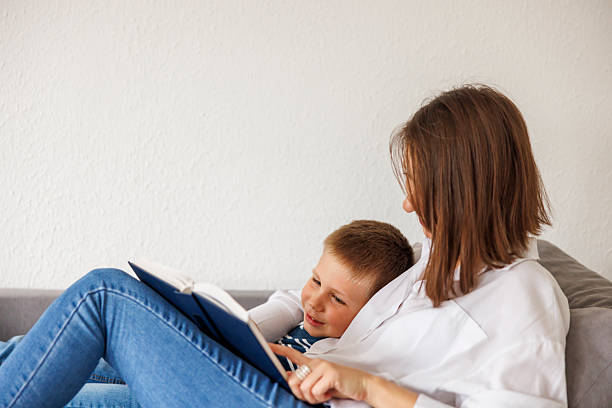 Top view of mother and son lying on the floor reading a book
