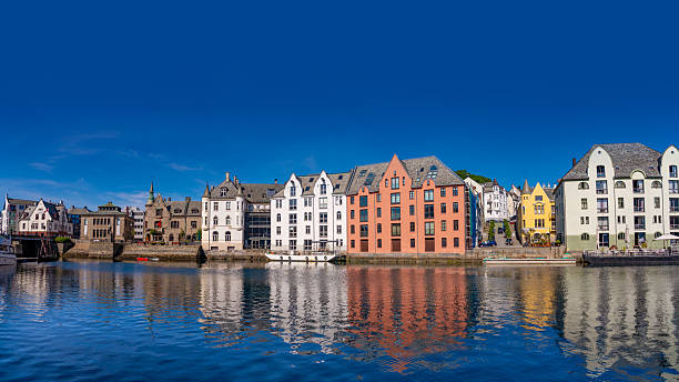 Colorful waterfront buildings in Alesund Norway reflecting on calm water under summer blue sky