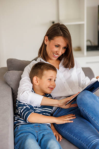istock Mother reading a book to a preschool age son while relaxing at home 2243585755