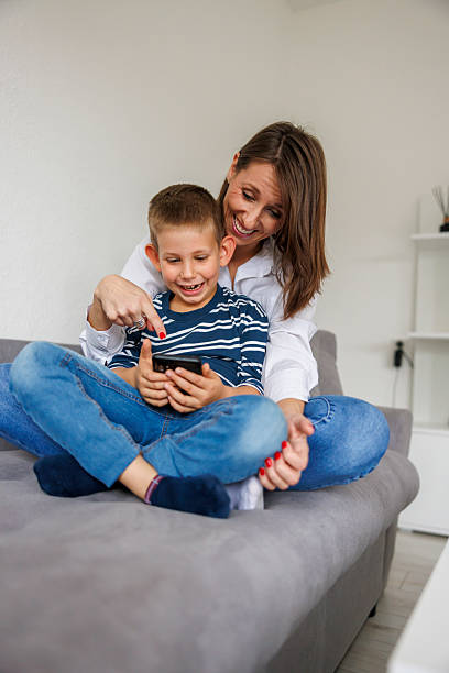 istock Mother and son having fun playing video games using smart phone at home 2243586048