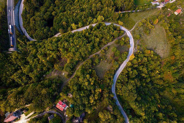 Aerial view showing a long winding road surrounded by green trees and buildings