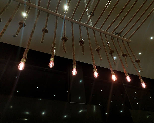 Rustic lighting fixture featuring ropes and glowing light bulbs. Stylish interior design element. Use for concepts relating to decor, artistry, or ambiance.