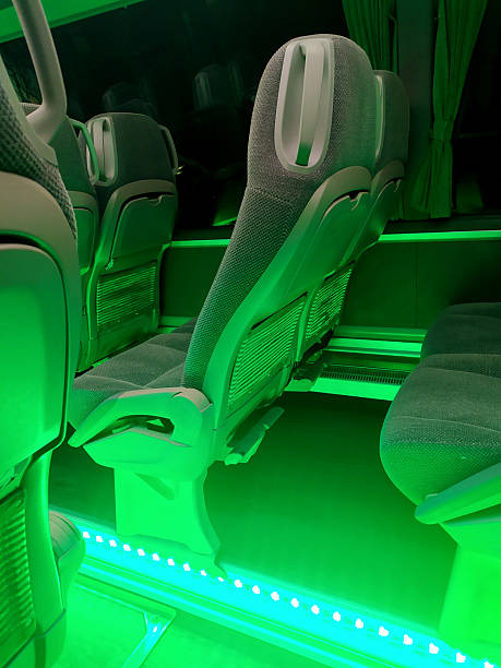 Interior of a bus illuminated by vibrant green light, highlighting rows of comfortable seating. Represents travel, modern design, and a unique ambiance.