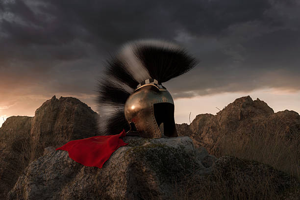 3D Rendering of ancient Illyrian helmet with black and white crest laying on rocks in the evening sunset