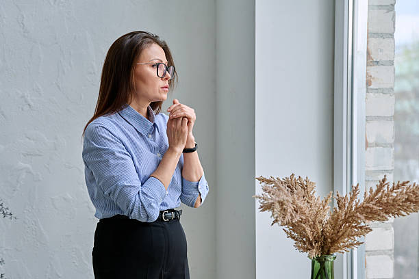 istock Mature tired, stressed woman standing near window 2243597502
