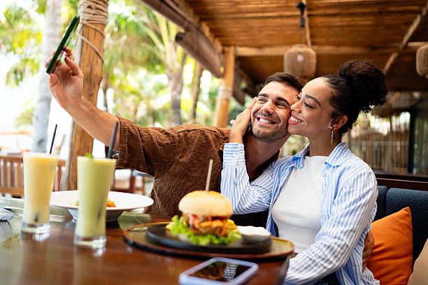 istock Young couple sharing dining experience at tropical restaurant, engaging with their online followers 2243598410