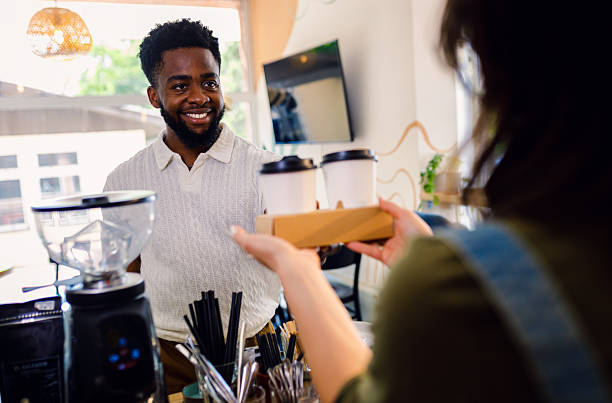 istock Smiling man taking a takeaway coffee from a barista in cafe. 2243600155