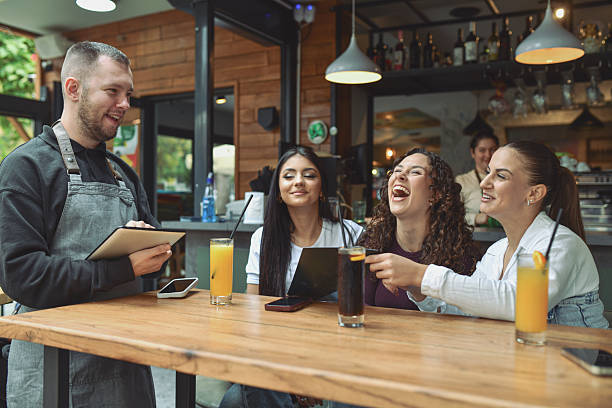 istock Friends At A Lounge Bar Enjoying Breakfast And Drinks While A Handsome Waiter Serves In A Modern Café Scene 2243602176