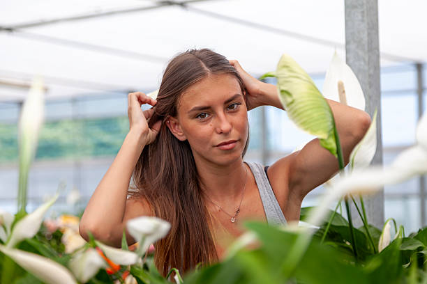 istock Young woman posing casually surrounded by peace lily plants, natural light on her face 2243602989