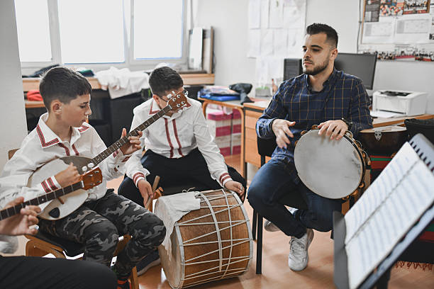 istock Teacher Playing Traditional Instrument Together With Young Boys During Lesson Activity 2243605065