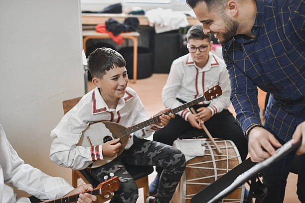 istock Male Instructor Helping Students Play Traditional Instruments During Engaging Classroom Music Session 2243607212