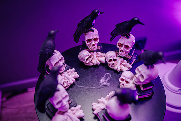 istock Decorative skulls and crows arranged in a circle on a dark surface, creating a spooky Halloween atmosphere with vibrant purple lighting 2243607758