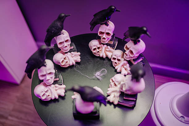 istock Halloween-themed table display featuring skulls and crows arranged in a circle, creating an eerie atmosphere with purple lighting and dark textures 2243607763