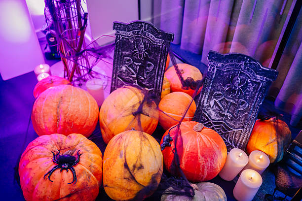 istock Colorful pumpkins with spooky decorations and candles create a festive Halloween atmosphere, featuring tombstones and spider webs for a haunting effect 2243608012