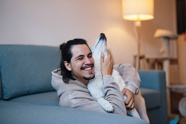istock Man relaxing on sofa while playing with his dog stock 2243610224