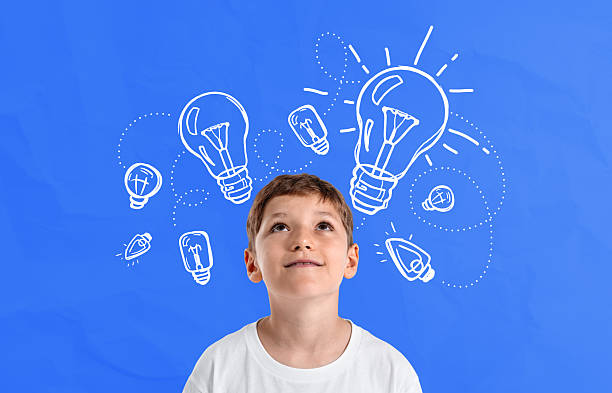 istock Curious boy imagining ideas with drawn light bulbs on blue backg 2243612119