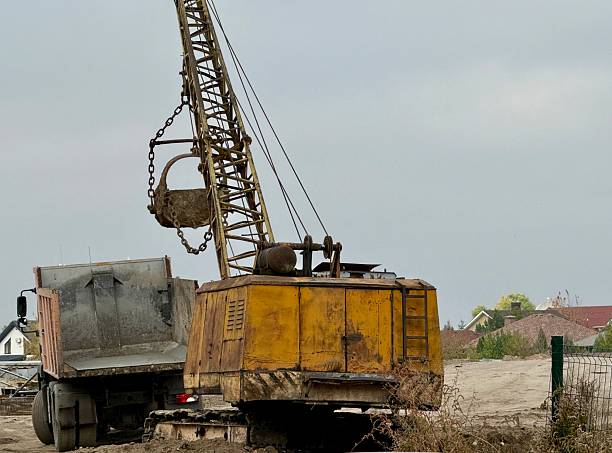 istock Old Excavator Loading Sand into Truck at Construction Site 2243612481