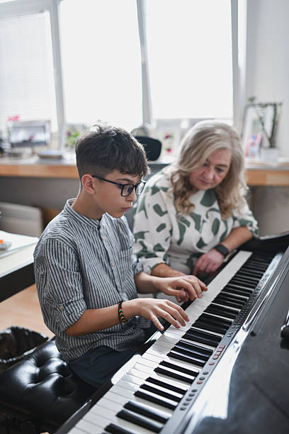 istock Young Student Playing Piano As Female Instructor is Listening Carefully During Music Class 2243613573