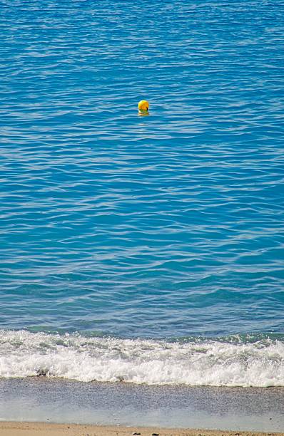 istock Tranquil beach scene with yellow buoy and clear blue sea. 2243613616