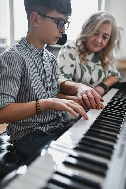 istock Instructor Gently Guiding Teen’s Hand Onto Piano Keys During Focused Practice Session 2243614193