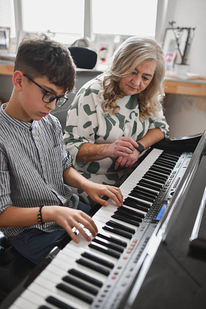 istock Focused Instructor Watching Teen Pianist Practicing Piece During Concentrated Lesson 2243614496