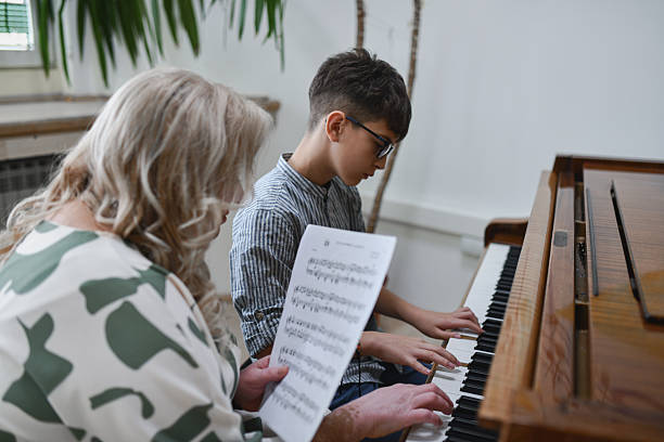 istock Female Instructor Holding Music Sheet Guiding Student While Practicing Piano Piece 2243615651