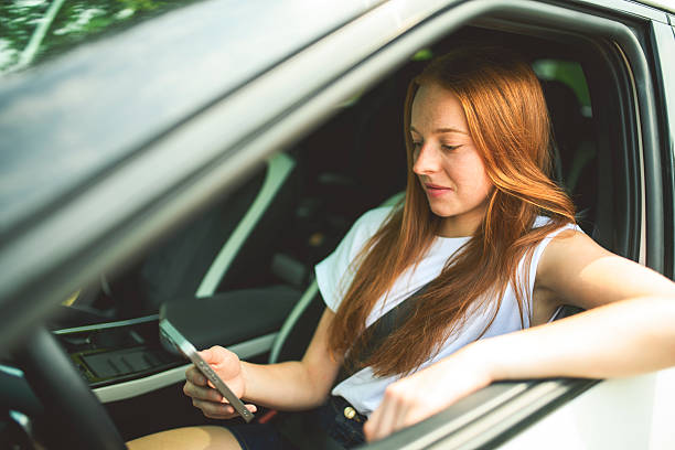 istock Beautiful young girl driver with with her white car using cellphone 2243619328