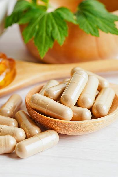 istock Herbal supplements in wooden spoon with green leaves background 2243619329