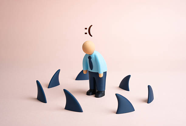 istock A tired office worker surrounded by shark fins. Business problems. Debt and falling income 2243619397