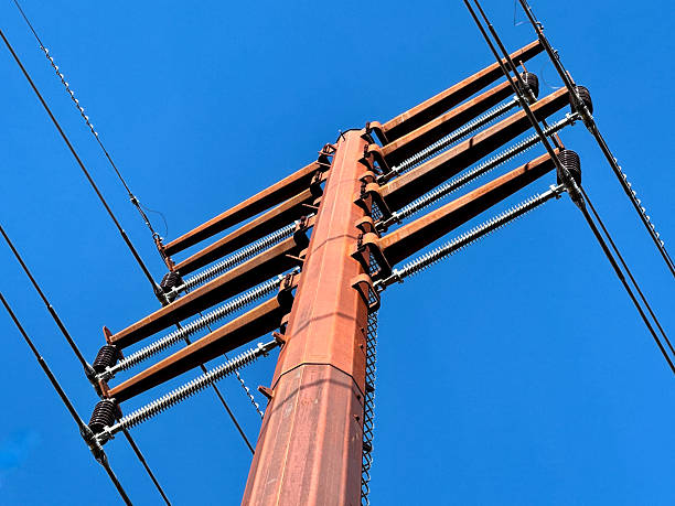istock EX CU low angle top of tall metal power line pole under blue sky 2243621180