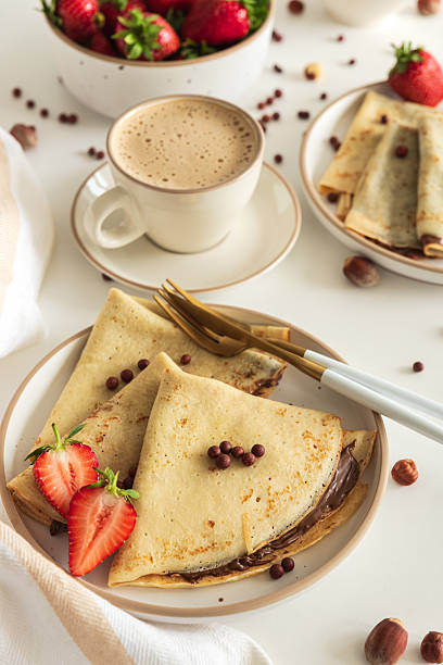 istock Crepes with chocolate hazelnut spread, strawberries and hazelnuts on a white wooden table. 2243621982