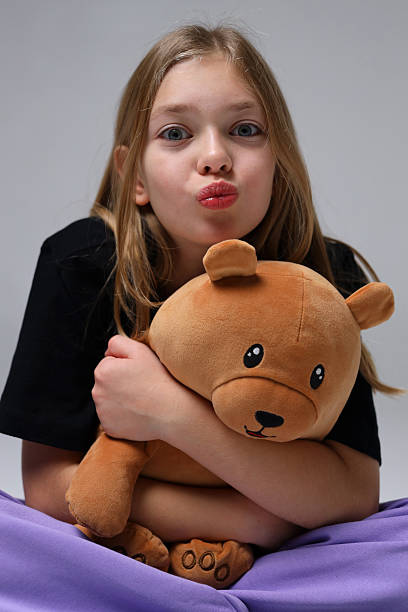 istock Caucasian female child hugging teddy bear with playful expression 2243627085
