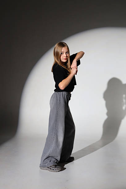 istock Young caucasian female performing dance pose in studio with spotlight 2243627107