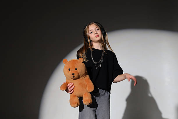 istock Young caucasian girl dancing with teddy bear in spotlight 2243627142