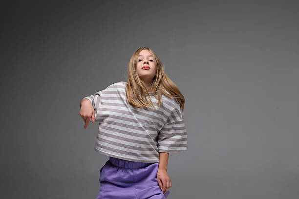istock Young caucasian female in striped sweater dancing joyfully in studio 2243627244