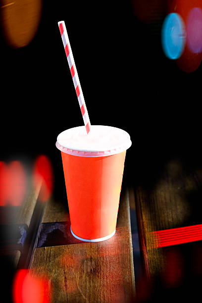 istock Orange drink cup with straw on wooden table. 2243628217