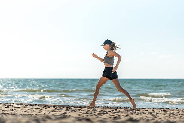 istock Woman runs beach, Female runner maintains steady pace by seaside 2243630906
