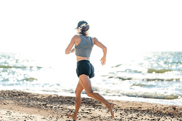 istock Sundrenched shoreline with casual female runner in silhouette 2243630919
