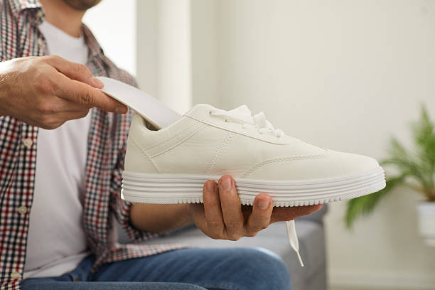istock Young man puts new orthotic insoles inside his comfortable white orthopedic shoes 2243631988