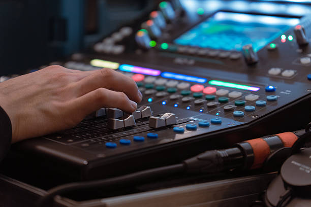 istock Sound engineer adjusting audio mixing console with colorful lights and controls in studio or live concert setup 2243633790