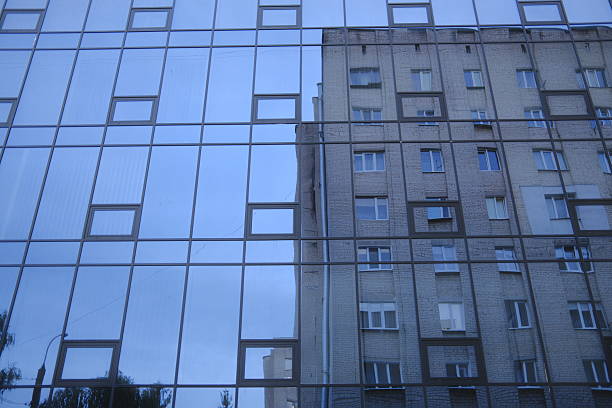 Modern facade reflects old in urban scene, cloudy day.