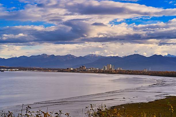 Scenic view of Anchorage skyline with mountains and cloudy sky in the background.