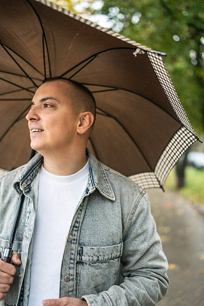 istock Man With Umbrella In Denim Jacket Exploring Rainy Park Atmosphere On A Quiet Autumn Day 2243650089