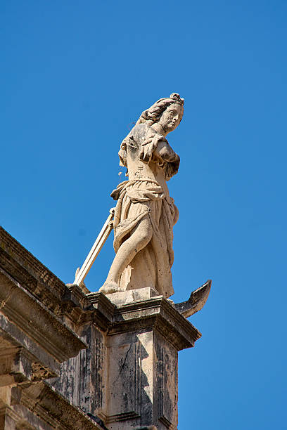 istock Weathered stone statue against a bright blue sky 2243650390